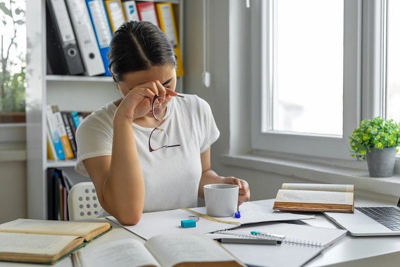 Tired woman surrounded by books and papers