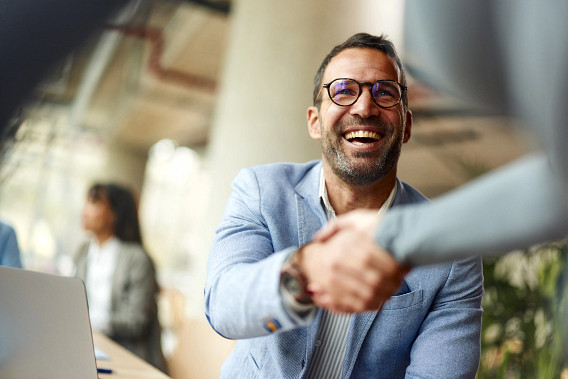 Smiling male business man shaking hands with a colleague while working in the office.