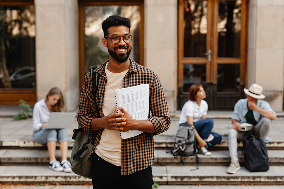 Students holding papers in front of building