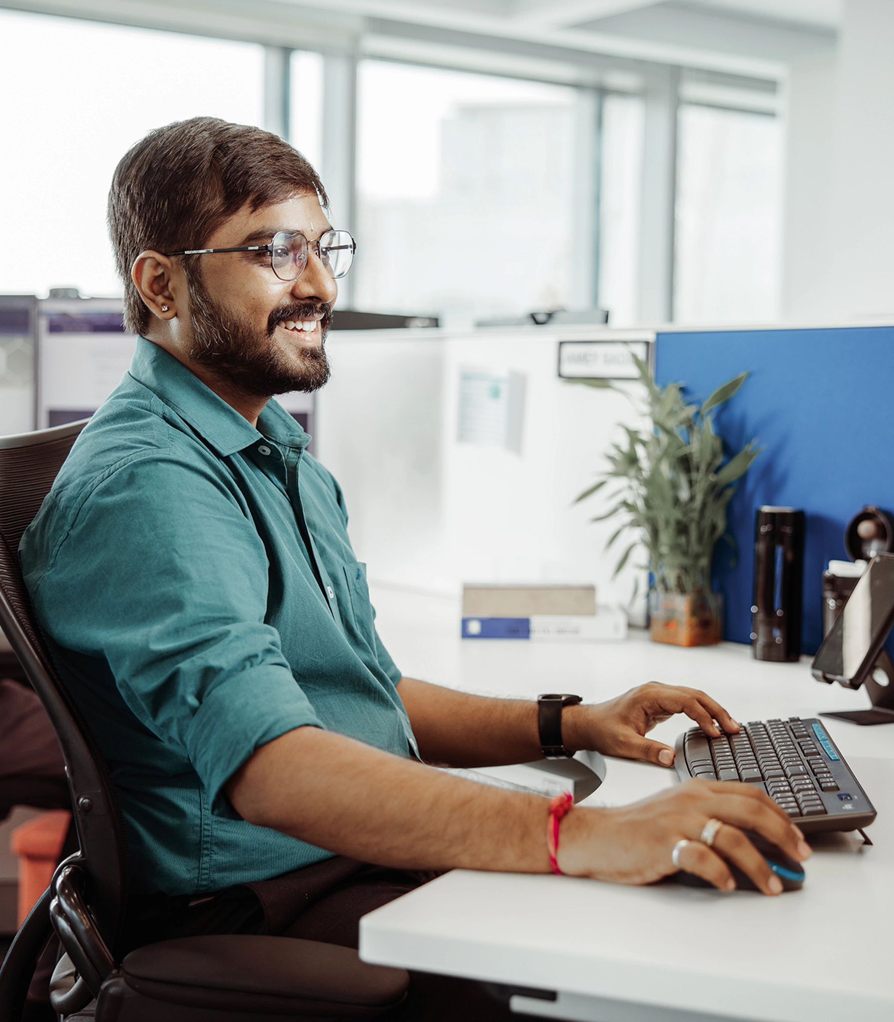 A smiling man sat at his desk working on his computer